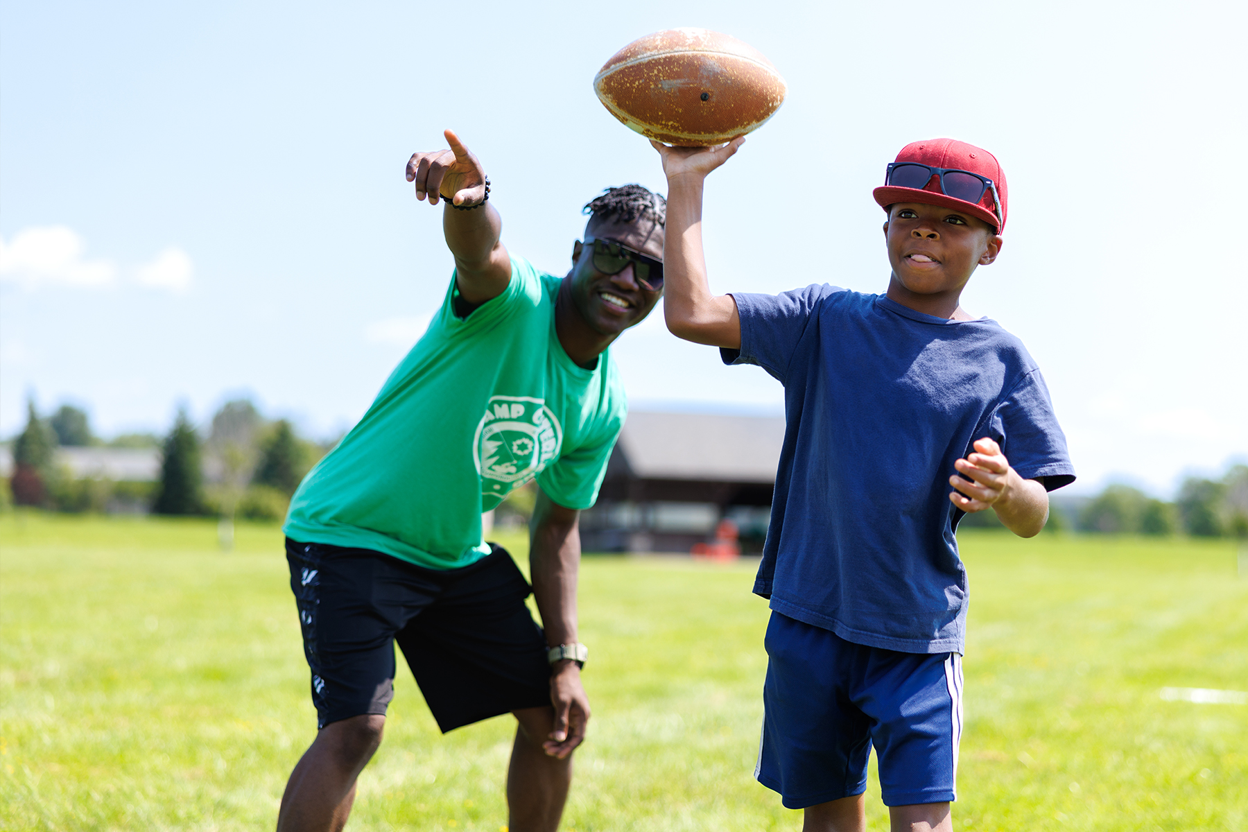 a counselor and a camper throwing a football in summer.